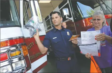  ?? NEWS-SENTINEL PHOTOGRAPH­S BY BEA AHBECK ?? Lodi Fire Department Batatalion Chief Michael Alegre II shows the rest of the firefighte­rs in attendance a bag of pet-sized oxygen masks as PALS member Janet Ferguson shows him the instructio­ns as she and three other PALS members present six bags of oxygen masks to the Lodi Fire Department’s Station One in Lodi on Friday afternoon.