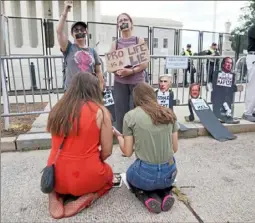  ?? Jacquelyn Martin/Associated Press ?? Anti-abortion activists Maggie Donica, left, and Grace Rykaczewsk­i, both 21, kneel and pray in front of abortion-rights protesters following the Supreme Court’s decision to overturn Roe v. Wade in Washington last month.