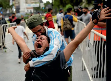  ?? AP ?? Mourners embrace as they wait to see Diego Maradona lying in state outside the presidenti­al palace in Buenos Aires.