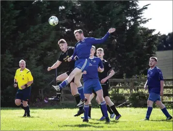  ??  ?? Aughrim’s John Ansley heads the ball clear.