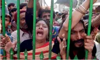  ?? AFP ?? Devotees weep as they gather outside closed gate of the shrine of Lal Shahbaz Qalandar in Sehwan on Friday. —