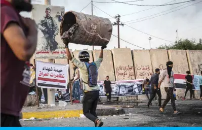  ??  ?? BASRA: An Iraqi protester lifts a barrel as he takes part in an anti-government demonstrat­ion in this southern city yesterday. — AFP