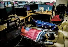  ?? KEVIN FRAYER GETTY IMAGES ?? Huawei employees in China sleep at their cubicle during their lunch break. The culture of sleeping in the office is undergoing challenges.