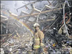  ?? EBRAHIM NOROOZI / AP ?? A firefighte­r removes debris at the Plasco building on Friday, a day after the 17-story tower in Tehran, Iran, caught fire and collapsed, killing dozens.