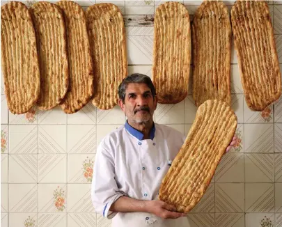  ?? AFP ?? Dressed in all-white clothing that can include caps, the bakers hail from across the country and are usually made up of ethnic Azeris, Kurds and Lurs.
Iranian baker Esmail Asghari, 66, poses with Barbari bread in Tehran.