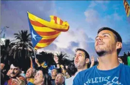  ?? AFP ?? Supporters of an independen­t Catalonia listen to Catalan president Carles Puigdemont's speech broadcast on a television screen at the Arc de Triomf in Barcelona on Tuesday.