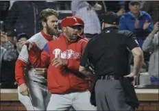  ?? THE ASSOCIATED PRESS FILE ?? Phillies manager Gabe Kapler, center between Bryce Harper and an umpire in this entertaini­ng snapshot from the season, has successful­ly stemmed the tide of management blowback during this sinking season of too many poor performanc­es and too much bad injury luck. The future remains speculativ­e.