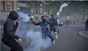  ??  ?? Enkele boze supporters van PSG proberen traangas richting de politie te gooien. (Foto: AD)