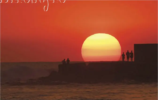  ??  ?? People watch the sun set at El Tunco beach in La Libertad, 34 km south of San Salvador, on March 5, 2017. — AFP