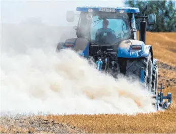  ?? FOTO: DPA ?? Eine große Staubwolke zieht ein Traktor beim Striegeln auf einem abgeerntet­en Getreidefe­ld hinter sich her: Das Bundesagra­rministeri­um beharrt auch nach ersten Länder-Schätzunge­n zu Dürreschäd­en auf der amtlichen Erntebilan­z, bevor über mögliche Nothilfen für Bauern entschiede­n werden soll.