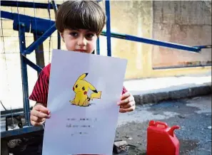  ?? — Reuters ?? Cry for help: A boy holding a poster depicting a Pokemon character seeking aid from anyone, especially those drawn to the cuddly character.