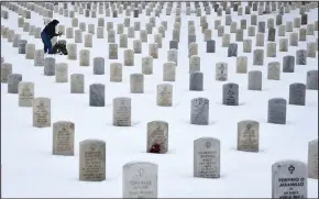  ?? ROBERT ALEXANDER/GETTY IMAGES ?? A woman places flowers on the grave of a loved one at the Santa Fe National Cemetery in New Mexico, which is administer­ed by the United States Department of Veterans Affairs.