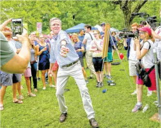  ?? — AP ?? AMHERST: Republican presidenti­al candidate former Florida Gov Jeb Bush (center) tries his hand at the pitching cage while participat­ing in the Fourth of July parade festivitie­s in Amherst, NH yesterday.