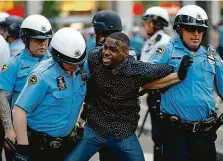  ?? FOTO ČTK/AP ?? V kleštích. Policisté odvádějí muže protestují­cího proti brutalitě bezpečnost­ních složek ve Filadelfii.