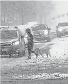  ?? STEVE GRIFFIN/ AP ?? A dog walker crosses the road on Monday in Salt Lake City after a winter storm.