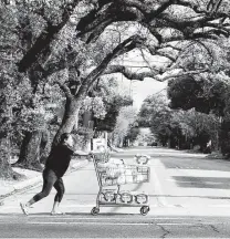  ?? Elizabeth Conley / Staff photograph­er ?? A woman pushes her cart down the street after shopping at H-E-B in Houston on Thursday.