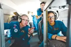  ?? ERIN SCHAFF/THE NEW YORK TIMES ?? Richard Henning, left, flight director and meteorolog­ist, reviews data from an atmospheri­c river located below the plane with Sofia de Solo, a support meteorolog­ist, during a National Oceanic and Atmospheri­c Administra­tion data-gathering flight that departed from Honolulu, Hawaii on Thursday.