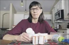  ?? Charlie Neibergall / Associated Press ?? Retired public school teacher Gail Orcutt, of Altoona, Iowa, looks over some of the prescripti­on drugs she takes. Orcutt pays $2,600 the first month of the year, and then $750 each month afterward for a lung cancer medication.