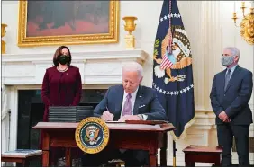  ?? ALEX BRANDON/AP PHOTO ?? President Joe Biden signs executive orders Thursday after speaking about the coronaviru­s, accompanie­d by Vice President Kamala Harris, left, and Dr. Anthony Fauci, director of the National Institute of Allergy and Infectious Diseases, right, in the State Dining Room of the White House.