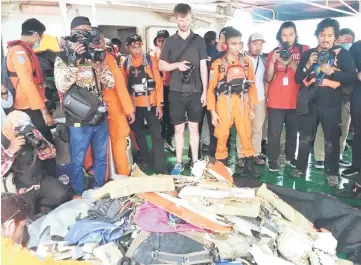  ??  ?? This handout photo taken and released by Indonesia’s National Search And Rescue Agency of Indonesia (BASARNAS) shows members of the media on a ship looking at wreckage retrieved at sea as search operations continue for Lion Air flight JT 610 which crashed into the sea off the northern coast of Indonesia’s Java island the day before. — AFP photos