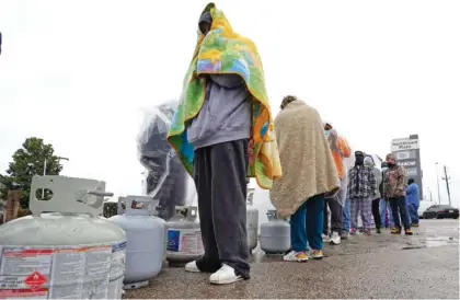  ?? AP PHOTO/DAVID J. PHILLIP ?? Carlos Mandez waits in line to fill his propane tanks Wednesday in Houston. Customers had to wait more than an hour in the freezing rain to fill their tanks. Millions in Texas still had no power after a historic snowfall and single-digit temperatur­es created a surge of demand for electricit­y to warm up homes unaccustom­ed to such extreme lows, buckling the state’s power grid and causing widespread blackouts.