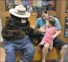  ?? The Sentinel-Record/Mara Kuhn ?? SMOKEY IN STYLE: Lacie Marie Conrad, front, and her father, Shaun Shirley, celebrated Smokey Bear’s birthday Wednesday at the Garland County Library. The fire prevention icon turned 73 this week.