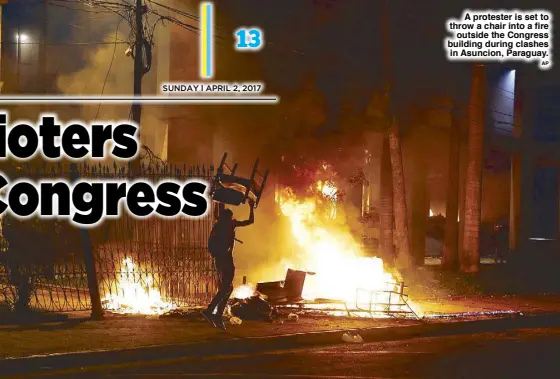  ??  ?? A protester is set to throw a chair into a fire outside the Congress building during clashes in Asuncion, Paraguay.