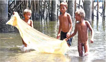  ?? MARK PERANDOS ?? INGENIOUS. Badjao kids try to catch fish using a mosquito net early in the morning at Isla Verde in Brgy. 23-C, Davao City.