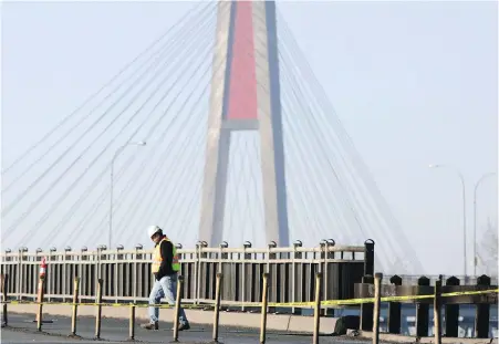  ??  ?? An engineer walks back across the road after assessing damage to the Pattullo Bridge in Surrey in 2009. A replacemen­t is coming for the aging Metro Vancouver bridge, which has an estimated remaining lifespan of about five years.