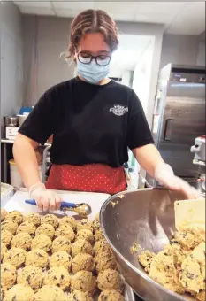 ??  ?? Mothership Bakery & Cafe’s helper Alyssa Soares makes cookies during a pre-Christmas dinner for area homeless, day laborers and anyone in need Wednesday.