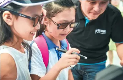  ?? MAO SIQIAN / XINHUA ?? Children participat­e in a trial of an intelligen­t device capable of facilitati­ng kids’ learning and medical diagnosis recognitio­n at a tech fair in Hong Kong.