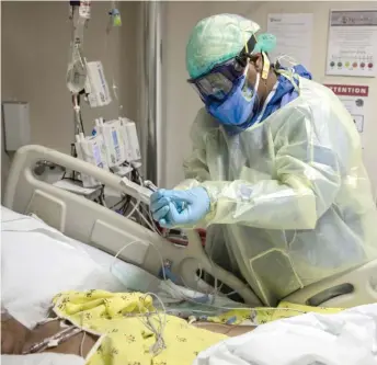  ?? ASHLEE REZIN/SUN-TIMES FILES ?? Nurse Tamara Jones checks the blood sugar levels of a 73-year-old woman with COVID-19 last year in the Intensive Care Unit at Roseland Community Hospital on the Far South Side.