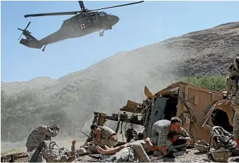  ?? AP ?? Specialist Paul Pickett, right, of the US Army’s Apache Company, 2nd Battalion 87th Infantry Regiment, covers an injured soldier as a helicopter lands to evacuate the wounded after their armoured vehicle hit an improvised explosive device in the Tangi Valley of Afghanista­n’s Wardak Province in August 19, 2009. President Joe Biden has announced he is putting the United States’ longest war to an end.