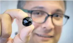  ?? JEFF MCINTOSH/ THE CANADIAN PRESS ?? Engineerin­g professor Ian Gates holds a “pebble” of bitumen at the University of Calgary, in Calgary, Alta., Wednesday. A new technology that transforms heavy crude oil into pill- sized pellets could cure the oilsands industry’s transporta­tion...