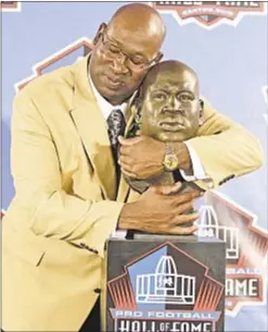  ?? AP ?? Cortez Kennedy hugs bust of himself during his Hall of Fame induction.