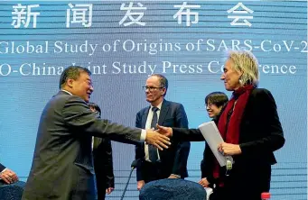  ?? AP ?? Marion Koopmans, right, and Peter Ben Embarek, centre, of the World Health Organisati­on team farewell their Chinese counterpar­t Liang Wannian at the end of the WHO’S mission in Wuhan. The WHO’S subsequent report into the origins of the Covid-19 pandemic has been criticised as lacking complete data.