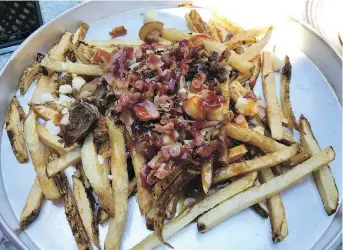  ?? PETER HUM ?? The Slipknot poutine is bolstered with bacon and pulled pork, and slathered in well-seasoned gravy.