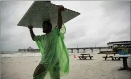  ?? ANDREW WEST — THE NEWS-PRESS VIA AP ?? George Nemr, an employee of Sunset Grill at Fort Myers Beach, Fla., removes chairs from the beach as a light rain falls on Friday. A possible tropical storm is forecast to arrive.