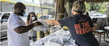  ?? CARL JUSTE / MIAMI HERALD STAFF cjuste@miamiheral­d.com ?? Volunteer Danayse Elias, right, distribute­s free meals. Food Rescue U.S. volunteers along with Chef Creole staffers prepared 300 meals to help restaurant workers who were hit hard by the pandemic,