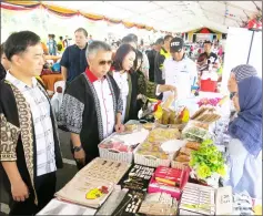  ??  ?? Snowdan ( second left) accompanie­d by Hii (left) and others, visits a stall at the compound of Sibu Indoor Stadium.