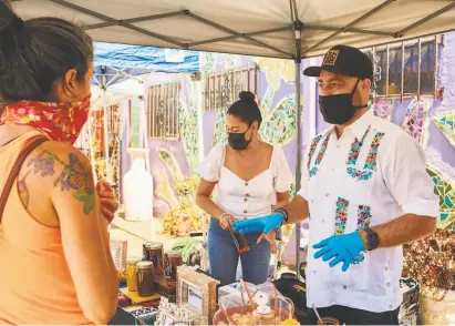  ??  ?? Janeen Mendoza Cruz (center) and Rodrigo Cruz Ayala, who own Oakland salsa company Kuali, at a popup.