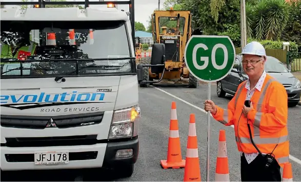  ??  ?? Reporter Mike Bain on the job as a stop-go traffic controller.