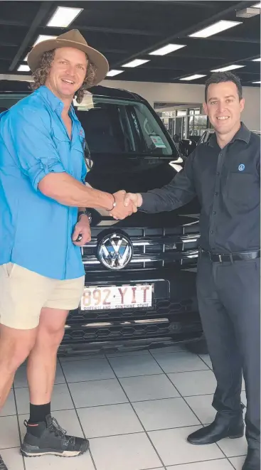  ??  ?? MAGNETIC PERSONALIT­Y: The Bachelor star Nick (The Honey Badger) Cummins with Cameron Atkinson at the Westco Volkswagen dealership in Cairns yesterday before he headed off the grid.