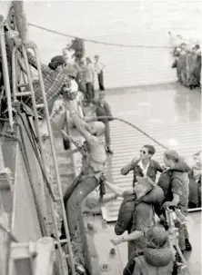  ?? Courtesy Le family 1975 ?? A sailor helps An Le and her mother, Hong Thi Le, board the Blue Ridge from a helicopter. Hung Le is at right in sunglasses.