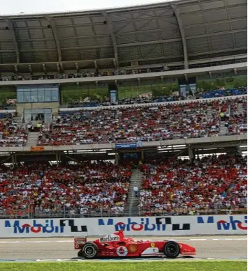  ?? Foto: Rainer Jensen, dpa ?? Michael Schumacher fährt 2004 durch das sogenannte Motodrom. Wenig später gewinnt er das Rennen. Damals waren die Tri bünen noch voll besetzt.