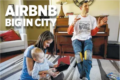  ?? STAFF FILE PHOTO BY DOUG STRICKLAND ?? Tom Sweets, right, talks at his Chattanoog­a home about how his family rents a room to out-of-town guests who book their stay through the website Airbnb, while his wife, Gabrielle, reads to their son, Isaac. The Sweets family is among a growing number...