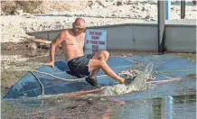  ??  ?? Steven Dobkins of Keys Marine Towing and Salvage works to clear a marina in Key Largo so he can retrieve damaged boats.