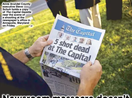  ?? AP ?? Anne Arundel County executive Steve Schuh holds a copy of The Capital Gazette near the scene of a shooting at the newspaper’s office in Annapolis, Maryland on Friday.