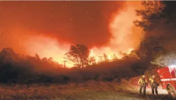  ?? NOAHBERGER/AP ?? Firefighte­rs watch the Bear Fire approach in Oroville, Calif., on Sept. 9. The blaze, part of the lightning-sparked North Complex, expanded at a critical rate of spread as winds buffeted the region.They work 50 hours at a stretch and sleep on gymnasium floors. Exploding trees shower them with embers. They lose track of time when the sun is blotted out by smoke, and they sometimes have to run for their lives from advancing flames. Firefighte­rs trying to contain the massive wildfires in Oregon, California and Washington state are constantly on the verge of exhaustion as they try to save suburban houses, including some in their own neighborho­ods.