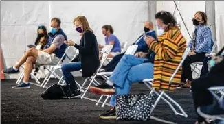  ?? ALYSSA POINTER / ALYSSA. POINTER@ AJC. COM ?? People gathered under one of the big white tents set up at the Dekalb Board of Health COVID- 19 vaccinatio­n site located at the Doraville MARTA transit station wait to receive their shots Monday.